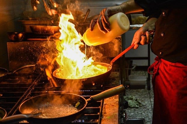 Photo of a chef setting a dish aflame in a saute pan
