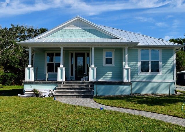 Front view of a single story home in the Shotgun Style painted teal blue with white trim.