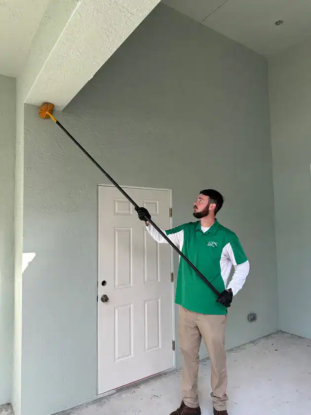 Green Pest Control service technician applying insecticide to the exterior of the house on Port St Lucie